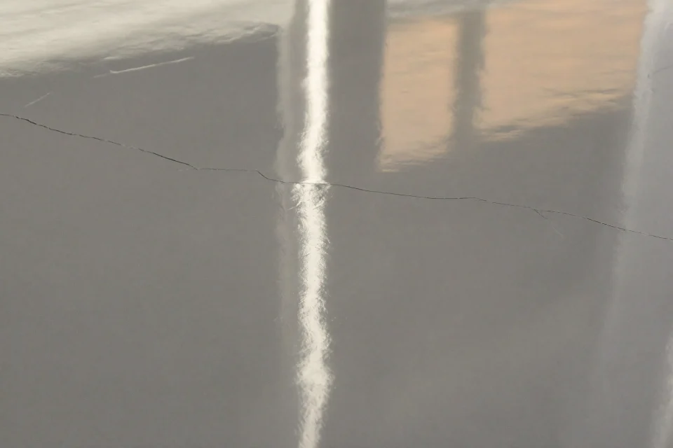 Glossy seamless grey resin floor with a faint old crack beneath the surface