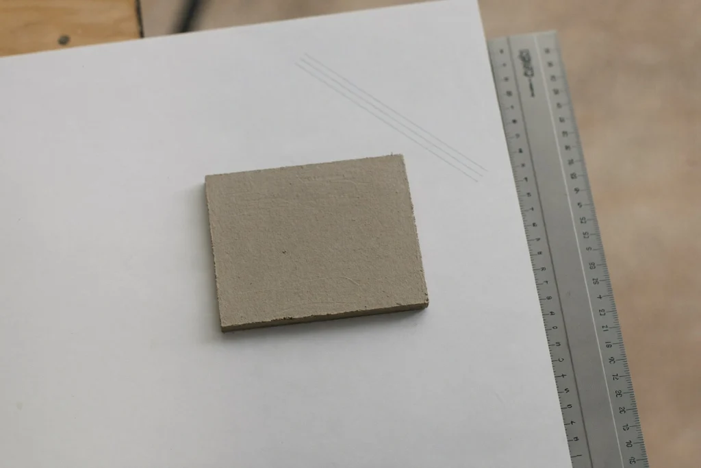 Grey poured resin sample and a steel ruler on a white drafting table
