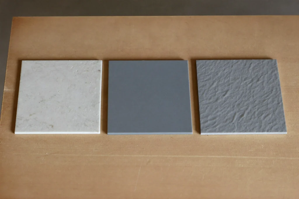 Three resin sample tiles, glossy, matte and textured, on a workshop bench